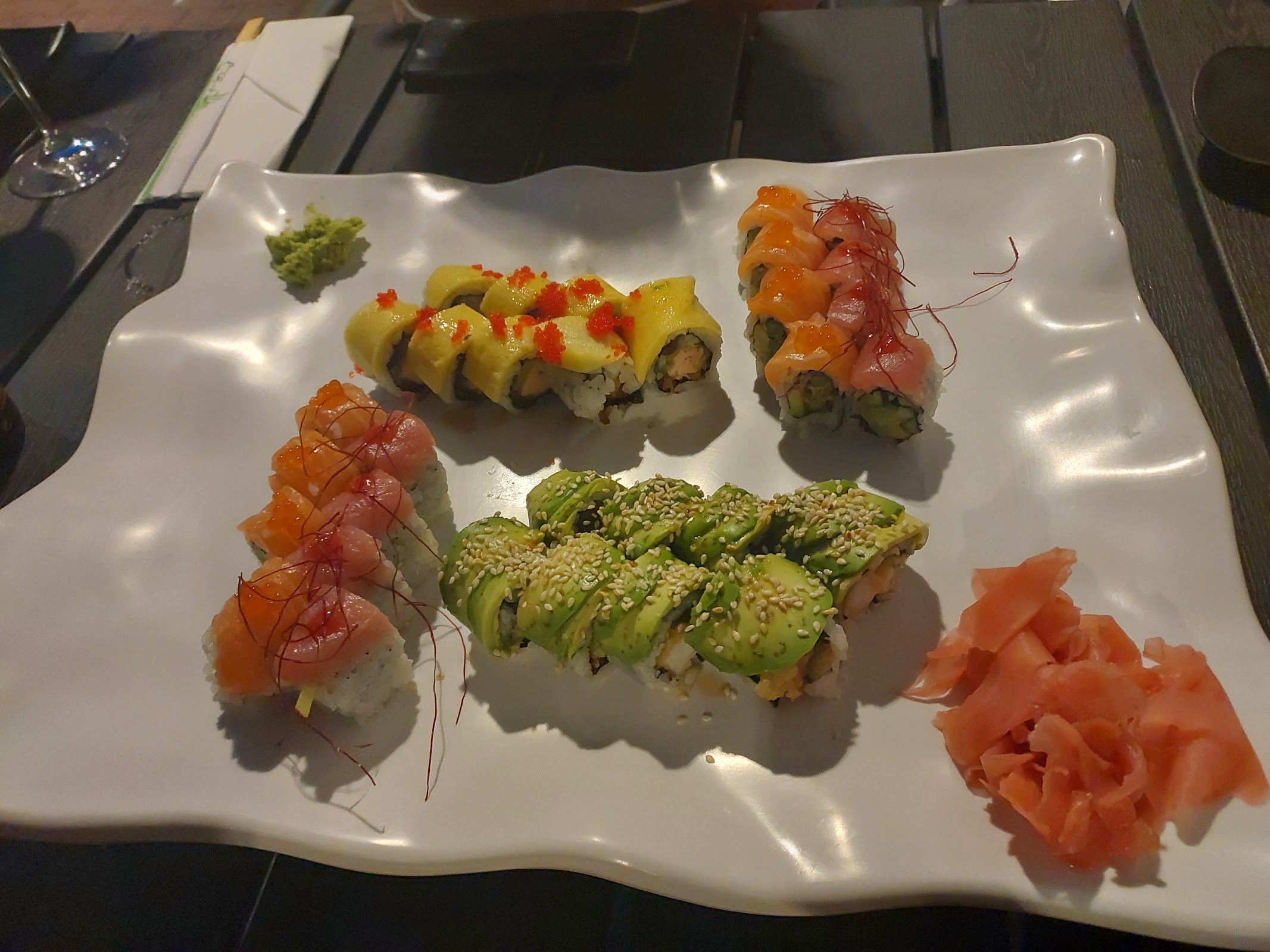Zestaw rolek sushi z łososiem, awokado i imbirem na białym półmisku
